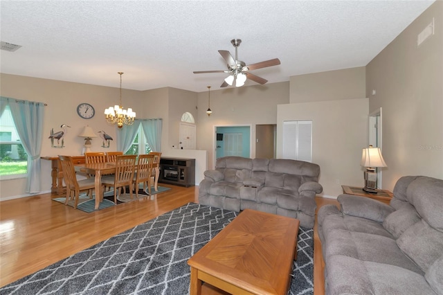 living room featuring wood-type flooring, ceiling fan with notable chandelier, and a textured ceiling