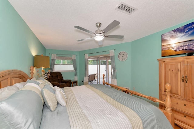 bedroom featuring ceiling fan, access to exterior, and a textured ceiling