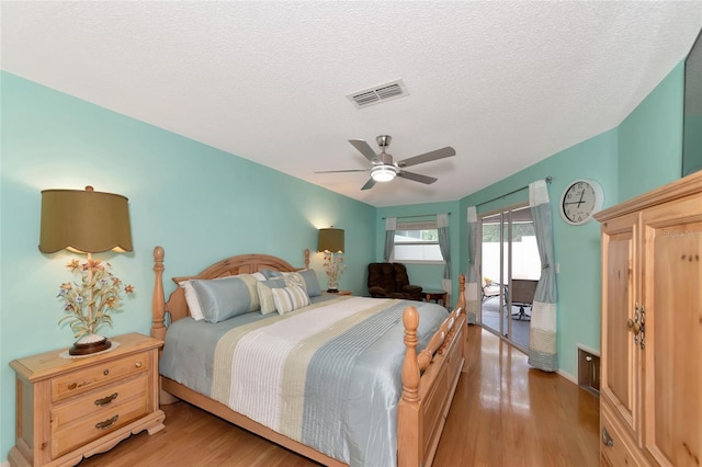 bedroom with access to exterior, a textured ceiling, ceiling fan, and light wood-type flooring