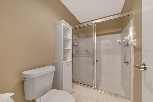 bathroom featuring tile patterned floors, toilet, and a shower with door