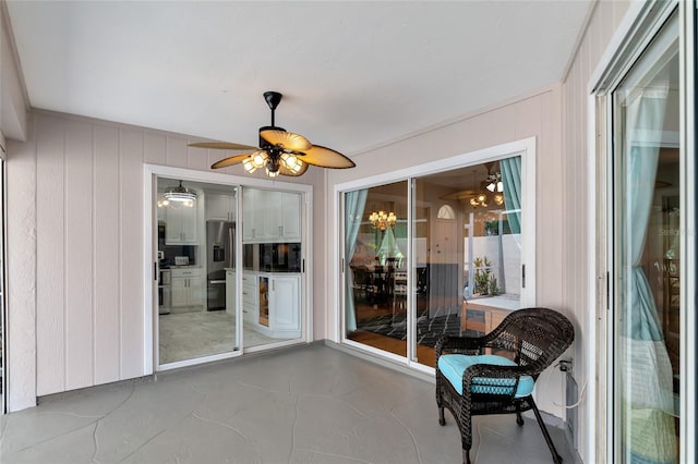 sunroom / solarium featuring ceiling fan with notable chandelier