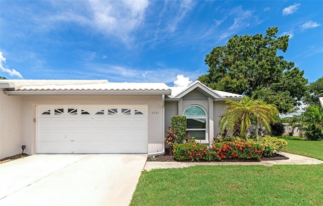 ranch-style home with a garage, a front lawn, concrete driveway, and stucco siding