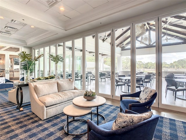 sunroom with a raised ceiling, ceiling fan, and plenty of natural light