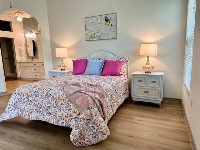 bedroom with ensuite bath, light hardwood / wood-style flooring, and multiple windows