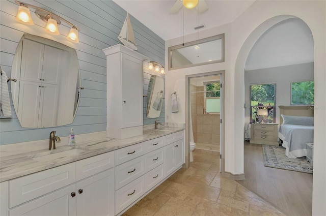 bathroom with walk in shower, vanity, ceiling fan, toilet, and wood walls