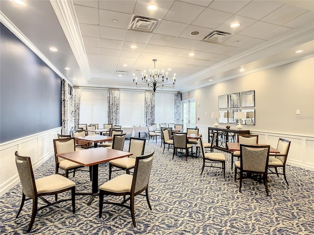 carpeted dining room with crown molding and a chandelier