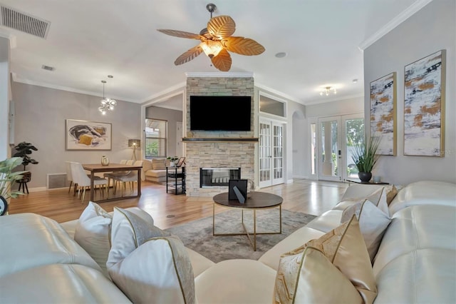 living room featuring crown molding, a stone fireplace, and light wood-type flooring