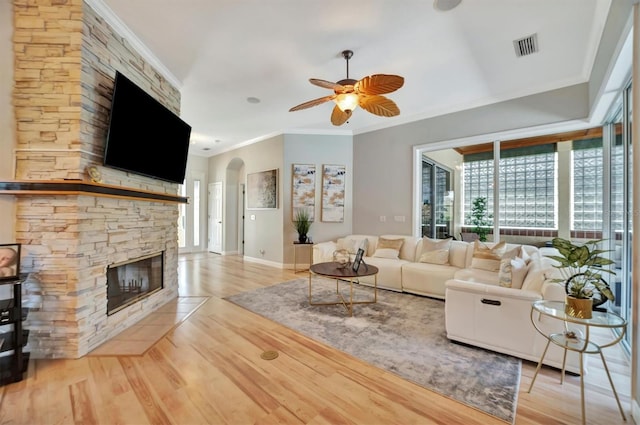 unfurnished living room featuring light hardwood / wood-style floors, crown molding, ceiling fan, and a fireplace