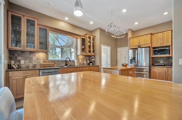 kitchen featuring backsplash, a kitchen island, sink, decorative light fixtures, and stainless steel appliances