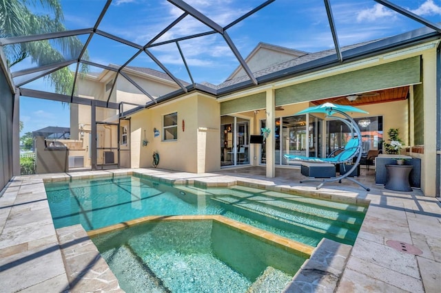 view of pool featuring ceiling fan, glass enclosure, an in ground hot tub, and a patio