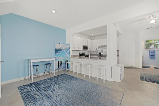 kitchen with kitchen peninsula, appliances with stainless steel finishes, sink, white cabinetry, and a kitchen bar