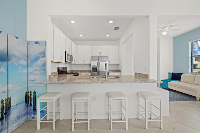 kitchen with kitchen peninsula, white cabinetry, a breakfast bar, and stainless steel appliances