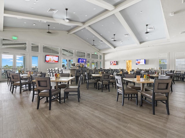 dining area featuring hardwood / wood-style floors, beamed ceiling, high vaulted ceiling, and a wealth of natural light