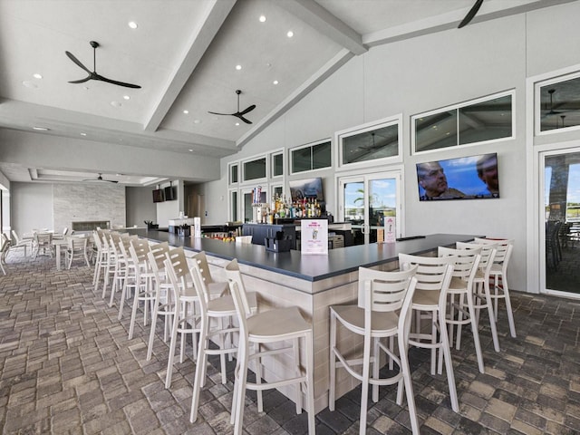 kitchen featuring beam ceiling, ceiling fan, high vaulted ceiling, and a kitchen bar