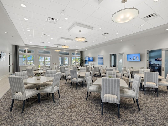 carpeted dining area featuring a paneled ceiling