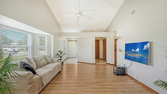 tiled living room with ceiling fan and high vaulted ceiling