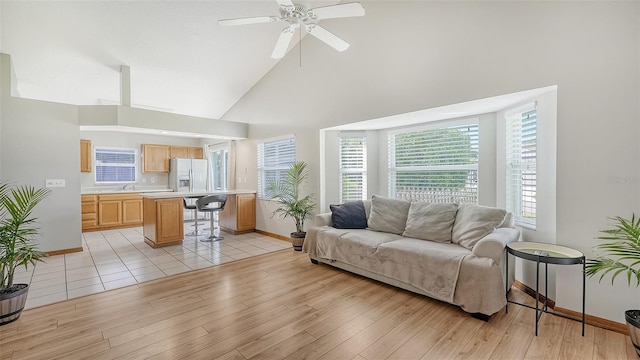 living room with ceiling fan, high vaulted ceiling, sink, and light hardwood / wood-style floors