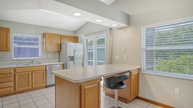 kitchen featuring a kitchen bar, appliances with stainless steel finishes, light tile patterned floors, sink, and lofted ceiling