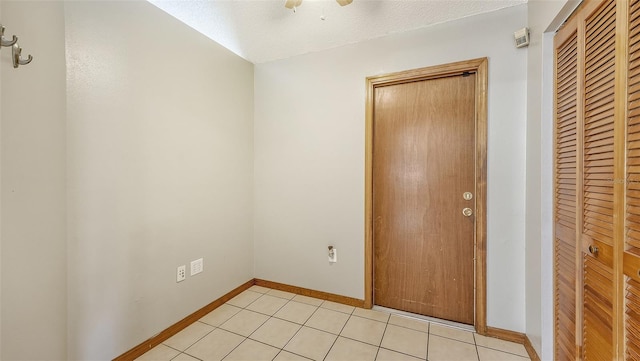 interior space featuring light tile patterned floors, ceiling fan, a closet, and a textured ceiling