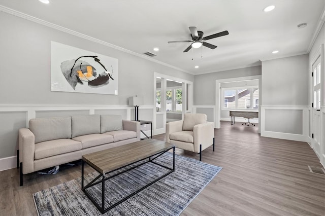 living room featuring hardwood / wood-style floors, ornamental molding, and ceiling fan