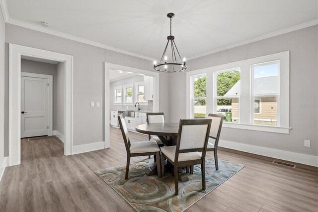 dining space with crown molding, a notable chandelier, and light hardwood / wood-style flooring