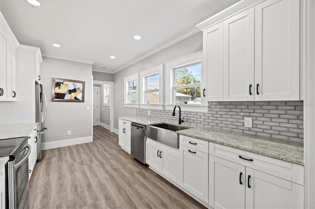 kitchen with stainless steel appliances, sink, white cabinetry, light stone counters, and tasteful backsplash