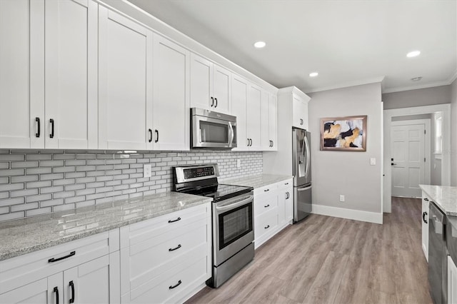 kitchen with stainless steel appliances, white cabinets, backsplash, light stone countertops, and crown molding