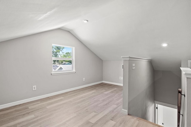 additional living space with light hardwood / wood-style floors and lofted ceiling