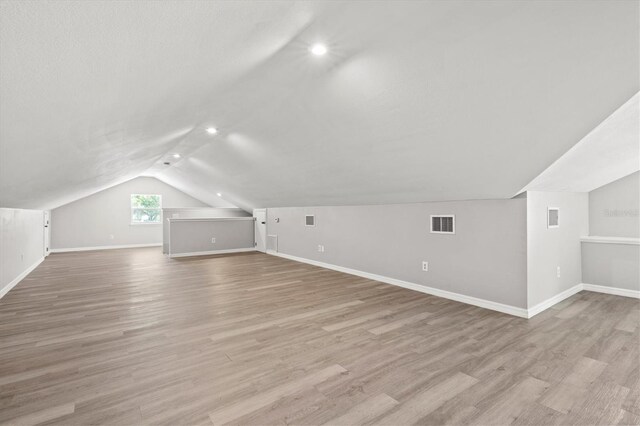 additional living space featuring light hardwood / wood-style floors and vaulted ceiling