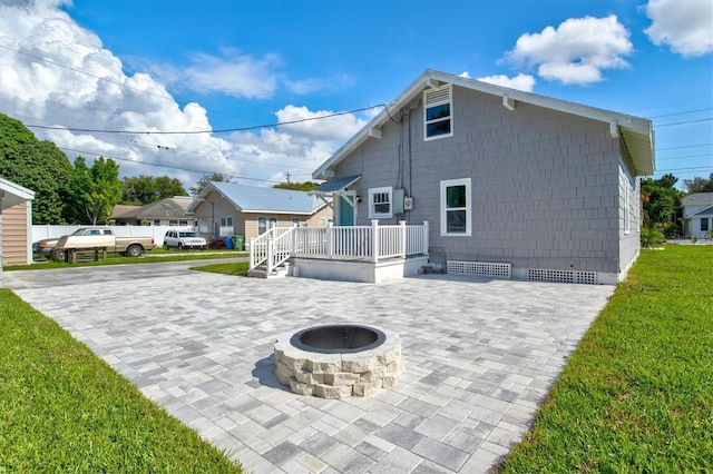 rear view of house featuring a fire pit, a patio, and a lawn