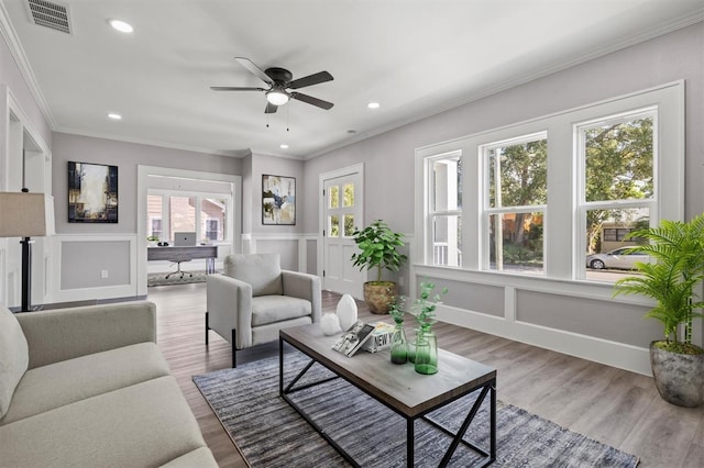 living room with hardwood / wood-style flooring, ceiling fan, and ornamental molding