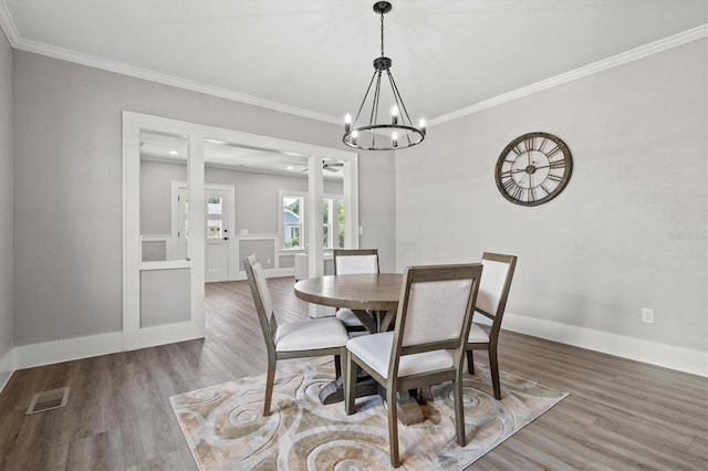 dining area featuring a chandelier, hardwood / wood-style floors, and crown molding