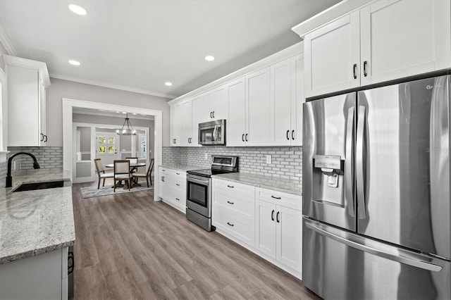 kitchen with stainless steel appliances, white cabinetry, sink, and tasteful backsplash