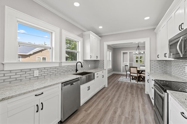 kitchen with stainless steel appliances, sink, white cabinetry, light hardwood / wood-style floors, and backsplash