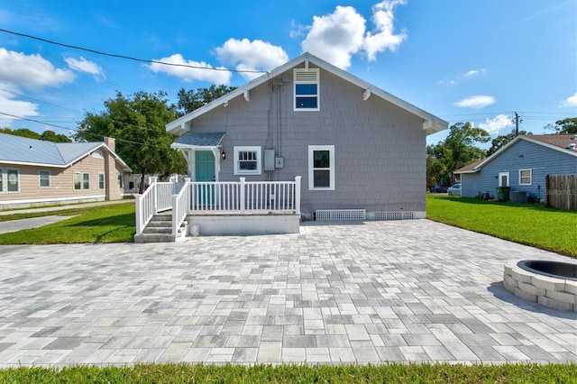 rear view of property featuring a fire pit and a yard