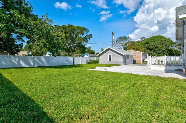 view of yard featuring a deck, an outbuilding, and a patio area