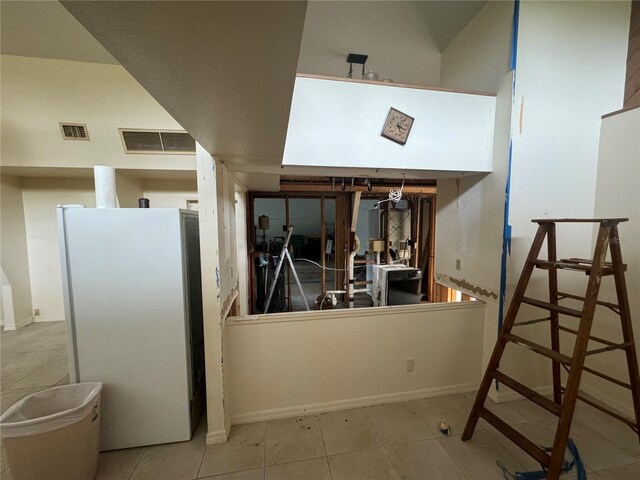 interior space with light tile patterned flooring, white fridge, and kitchen peninsula