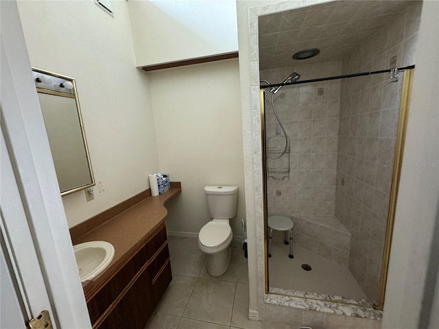 bathroom featuring toilet, tiled shower, vanity, and tile patterned floors