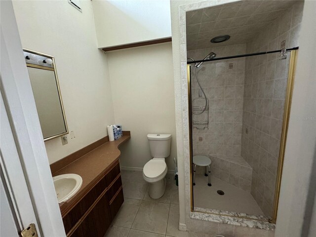 bathroom featuring vanity, tiled shower, tile patterned floors, and toilet