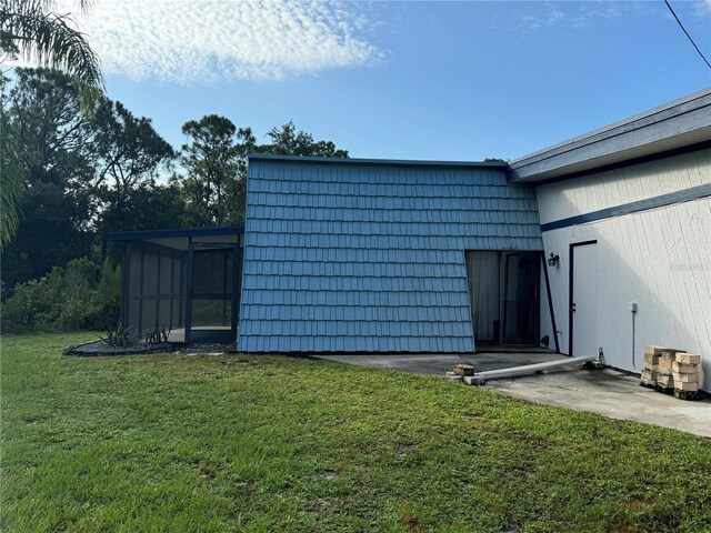 view of outbuilding featuring a yard and a sunroom