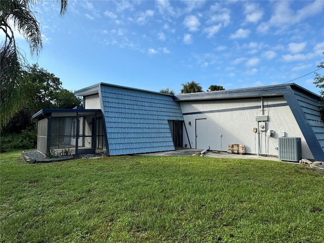 rear view of property with cooling unit, a sunroom, and a lawn