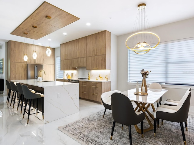 kitchen featuring a sink, hanging light fixtures, a center island with sink, and modern cabinets