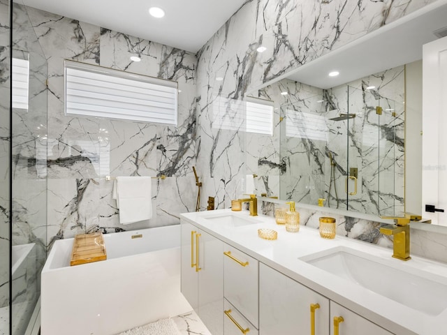 bathroom featuring stone wall, a freestanding tub, recessed lighting, a sink, and double vanity