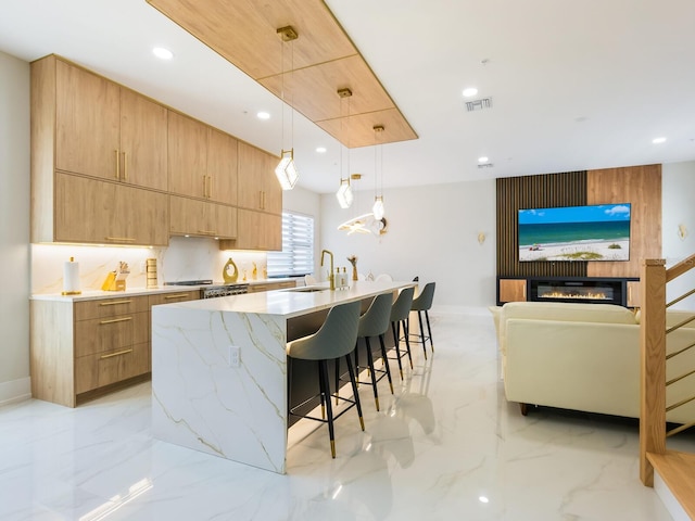 kitchen with hanging light fixtures, a large island, modern cabinets, and a sink