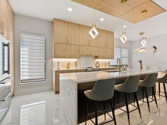 kitchen featuring pendant lighting, a center island with sink, and light brown cabinetry