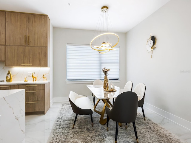 dining space featuring a chandelier, marble finish floor, and baseboards