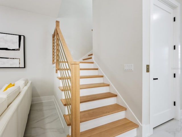 staircase with marble finish floor and baseboards