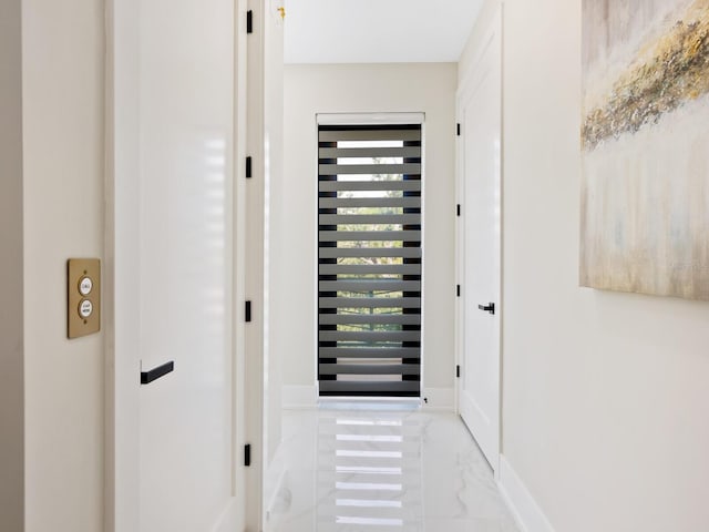 corridor featuring marble finish floor and baseboards