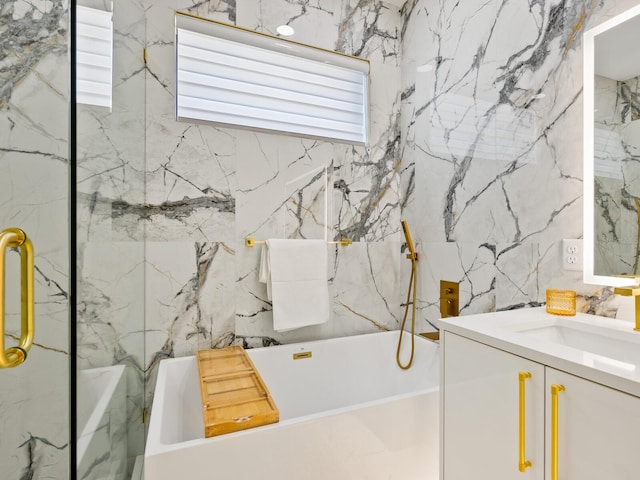 bathroom with a soaking tub, vanity, and stone wall