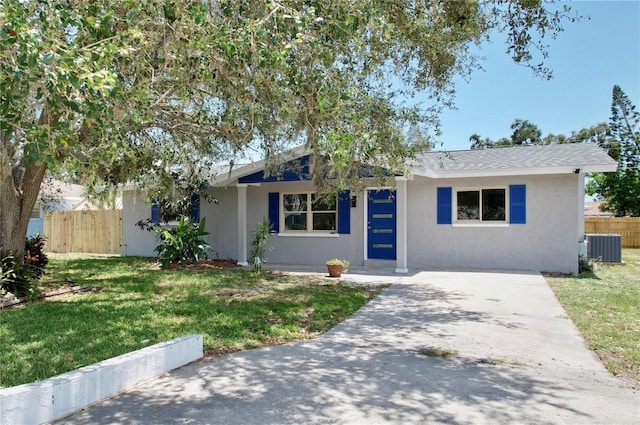 ranch-style home with fence, stucco siding, a front yard, and central AC unit